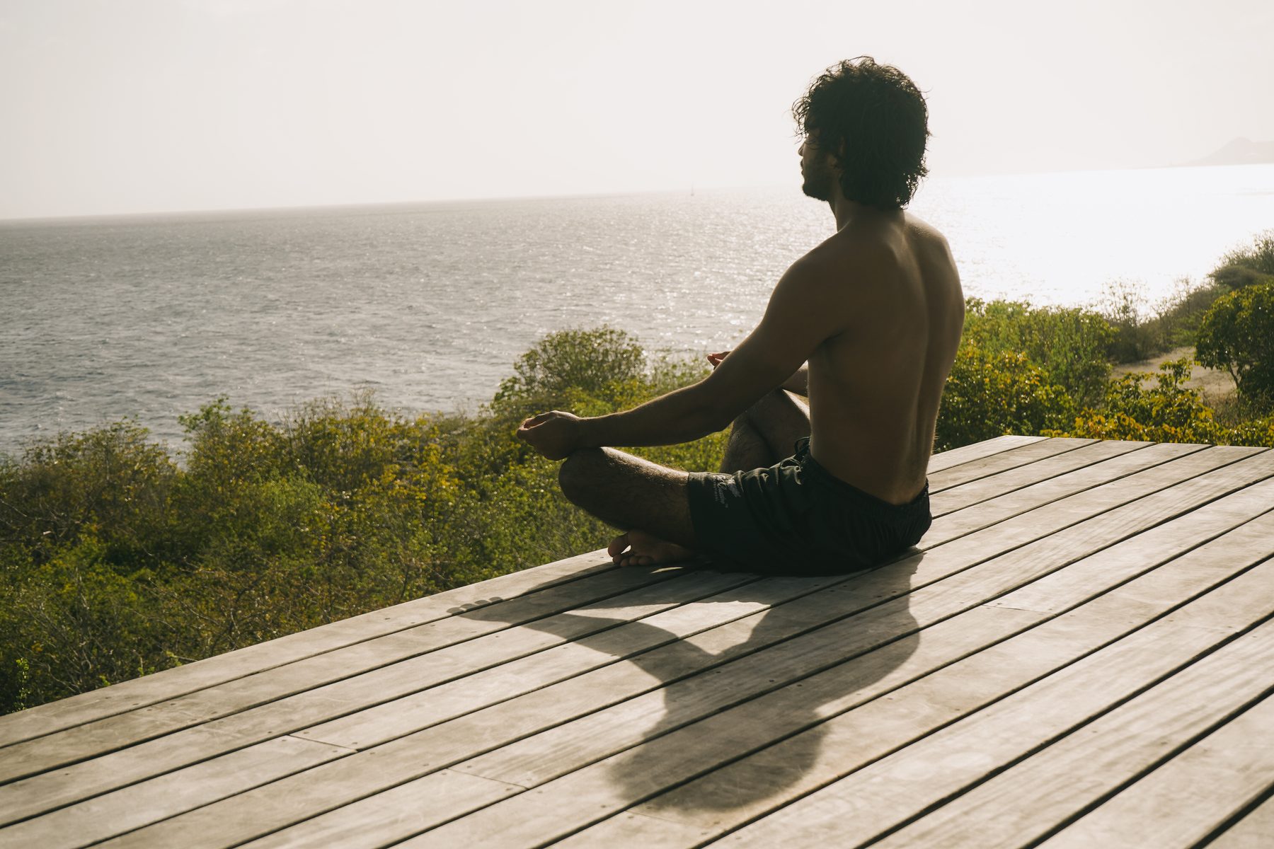 Man in a meditative pose, eyes closed, outdoors